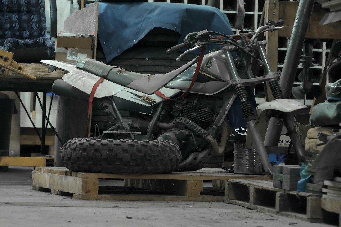 Ein zerlegtes Yamaha-Motorrad liegt auf Holzpaletten in einer Werkstatt.